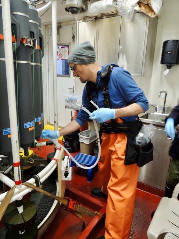 Photo of a UC Irvine Earth System Science professor named Brett Walker sampling Baffin Bay seawater.