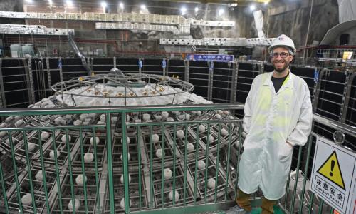 Physicist Pedro Ochoa-Ricoux stands next to JUNO particle detector under construction.